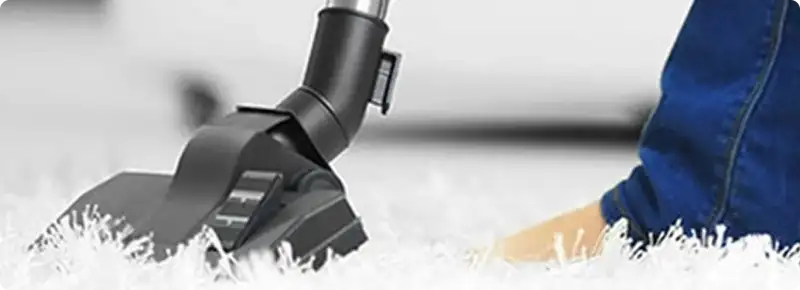 Close-up of a professional vacuuming a white carpet in Liverpool.