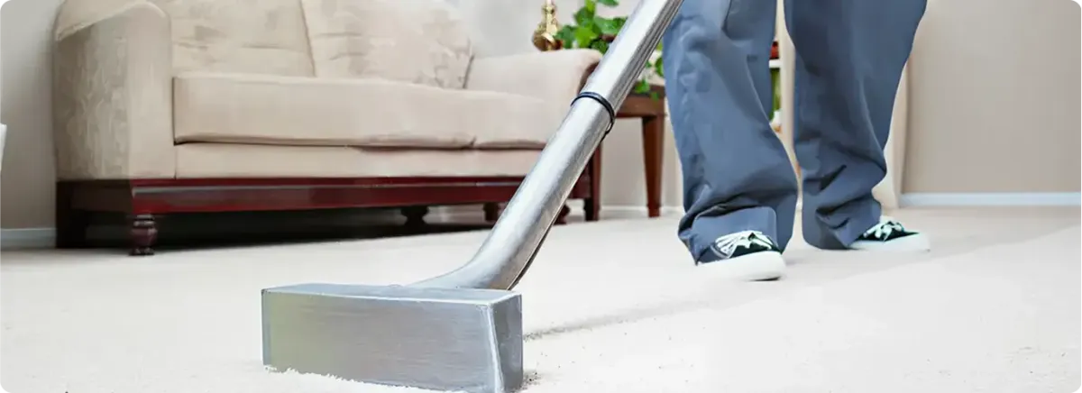 Carpet cleaning technician using a hot-water extraction wand on a light-colored carpet in a living room, Syracuse, NY.